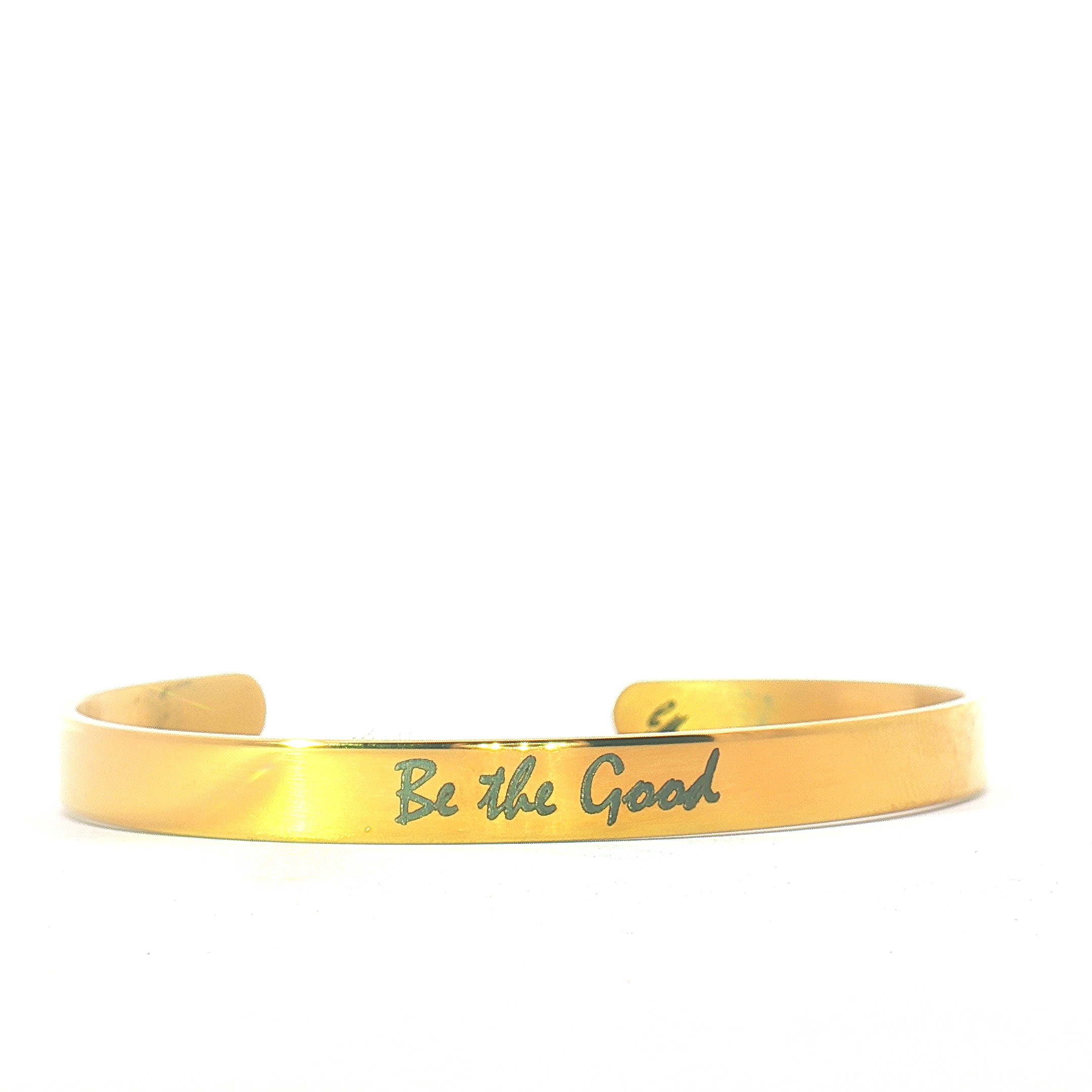 A gold metal bracelet with the engraved message Be the Good displayed on a plain white background.
